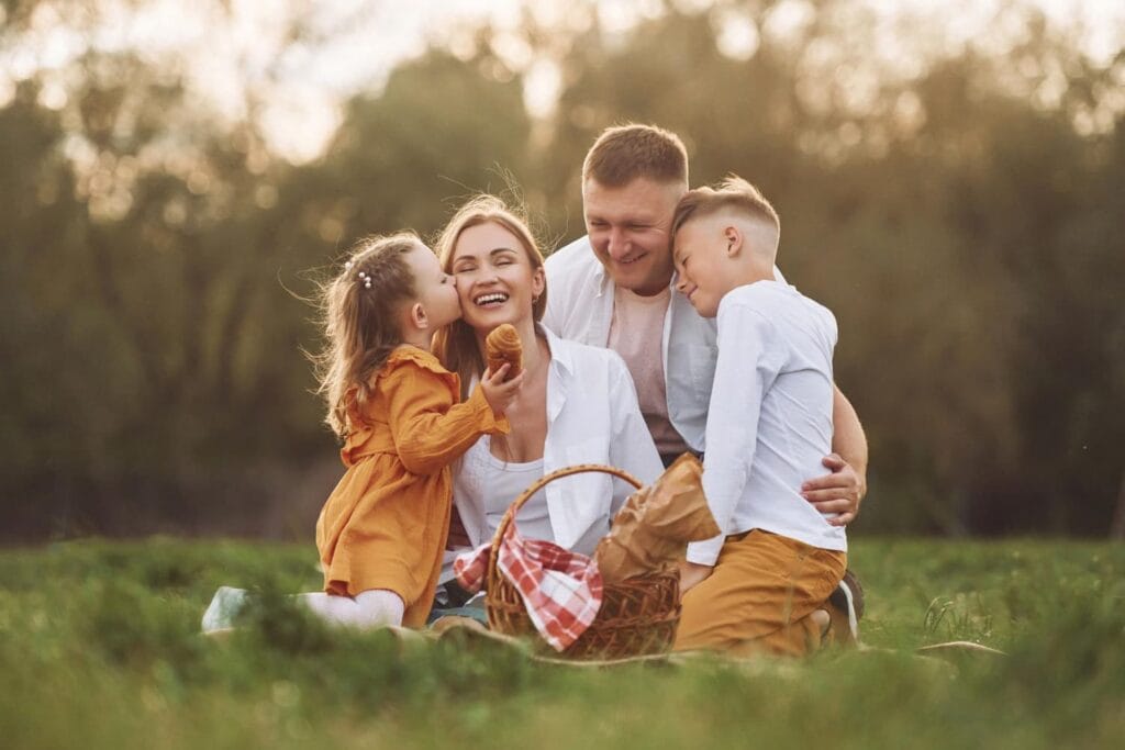 szcześliwa rodzina - mama, córka, syn i tata na pikniku w parku